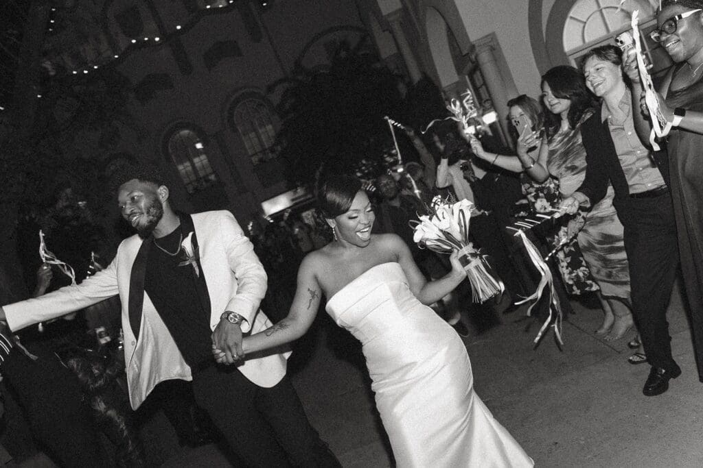 Joyful bride and groom running through guests during Morais Vineyards wedding exit