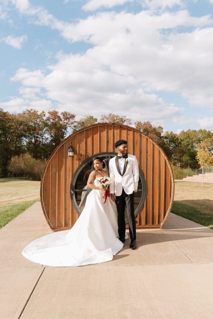Bride and groom posing outside Morais Vineyards wine barrel suite