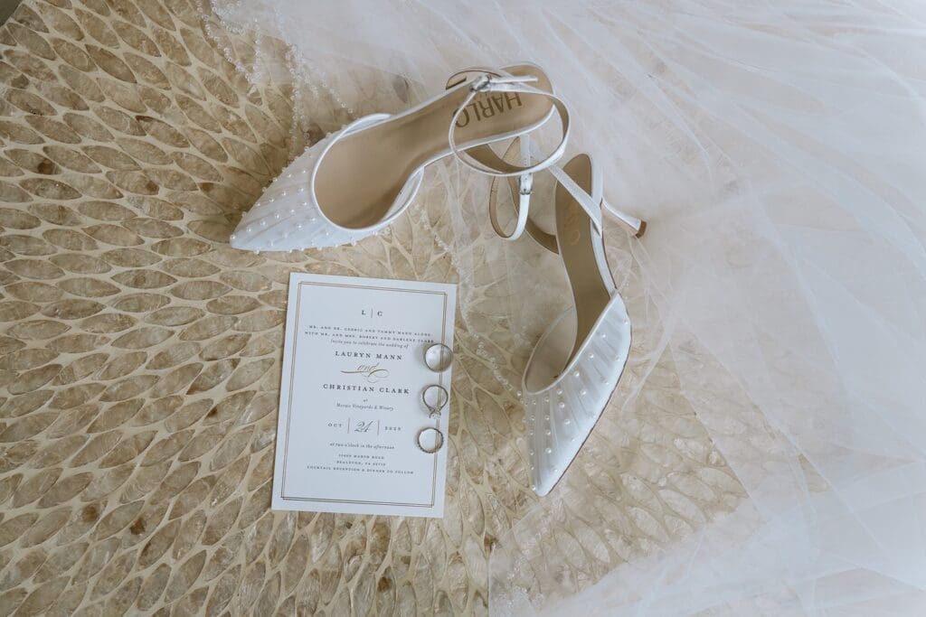 Wedding invitation, rings, and bridal shoes flat lay
