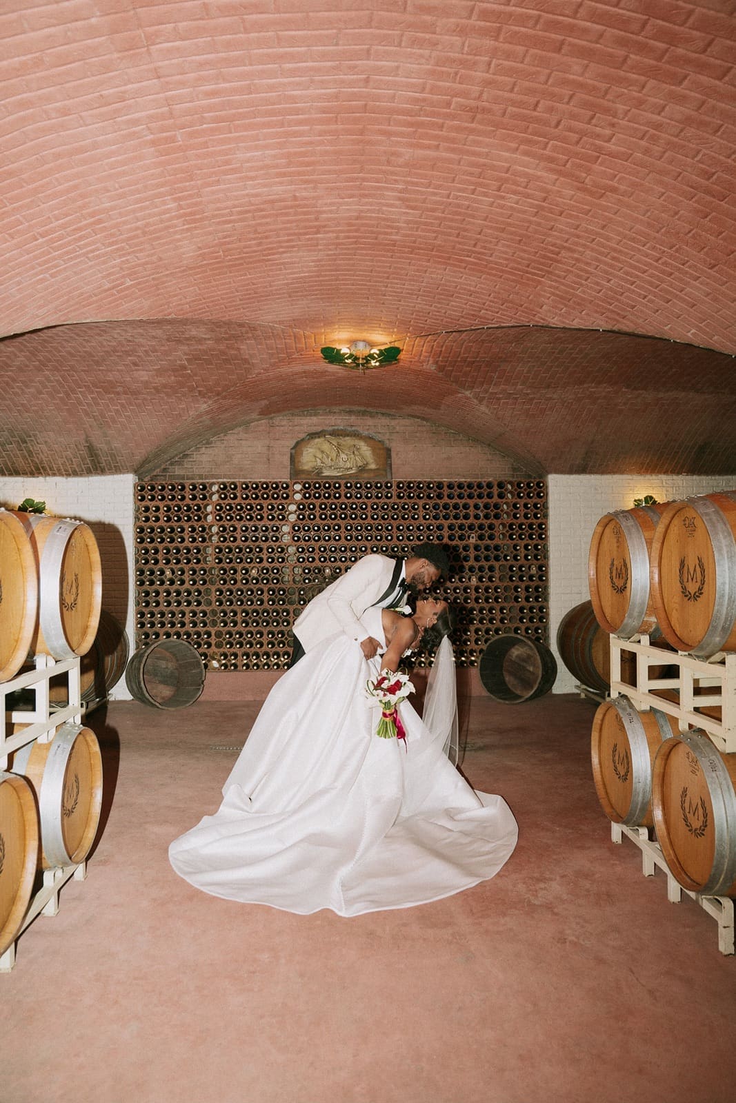 Bride and groom posing in Morais Vineyards wine cellar
