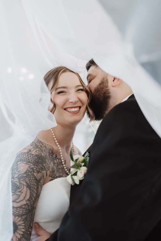 Bride and groom embracing and smiling inside The Woolen Mill in Fredericksburg, Virginia.