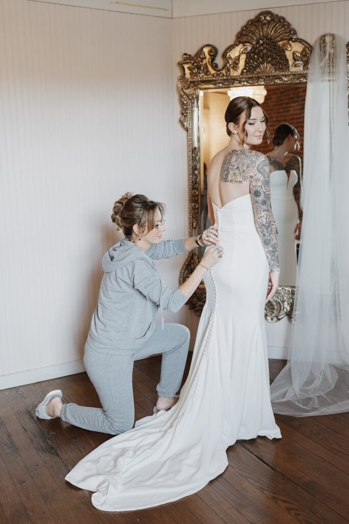 Mother helping the bride into her wedding dress before the ceremony.