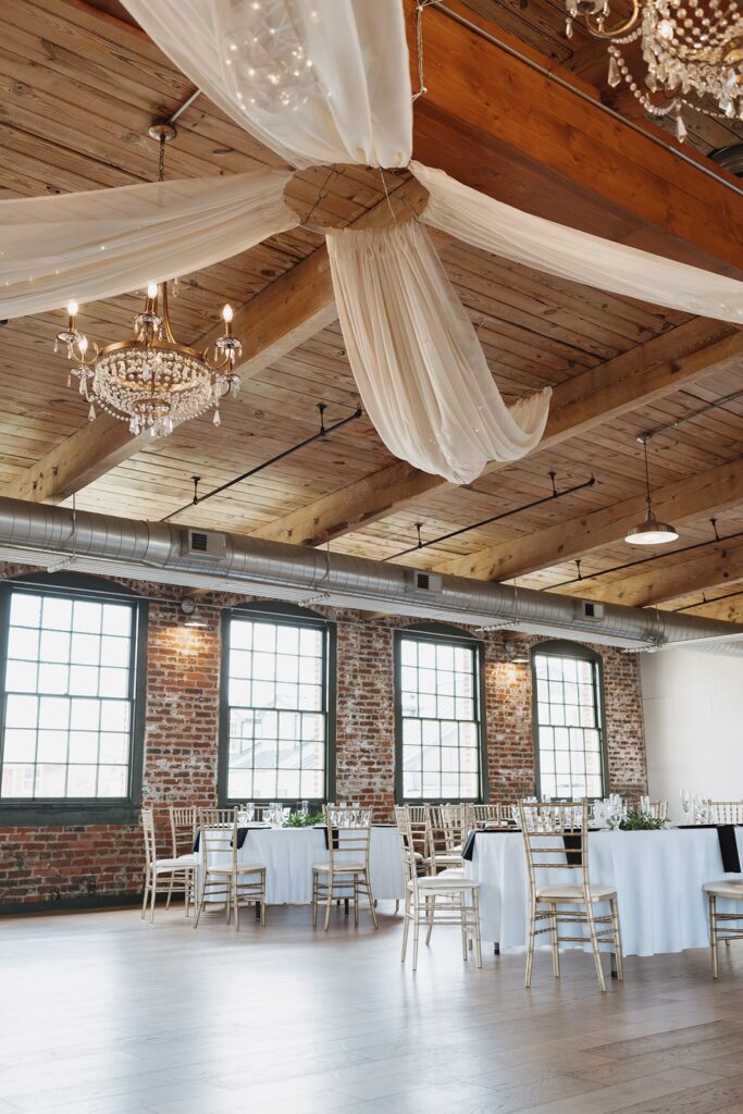 Wedding reception tables decorated with white flowers, greenery, and gold accents.
